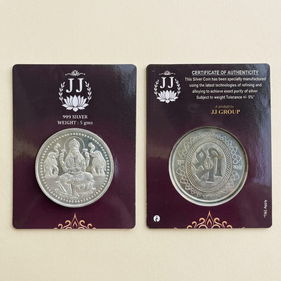 A silver coin displayed on two dark purple backing cards against a light beige background. The left card shows the coin with 'JJ GROUP' branding and '1999 SILVER WEIGHT 2.